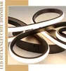 A close-up view of a modern, black LED ceiling light with curved, illuminated elements. Produktbild-Vorschau