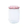 A clear studio shot of a glass jar with a red and white checkered lid. Produktbild-Vorschau