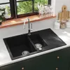 A black double basin granite sink with a chrome faucet is shown in a kitchen setting. Voir les images du produit