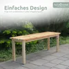 A wooden garden bench is placed on a paved patio in front of lush green bushes and trees. The image has a soft, blurred background and text overlays. Produktbild-Vorschau