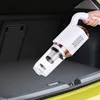 Weißer und roségoldener Handstaubsauger fürs Auto wird verwendet, um den dunkelgrauen Teppichboden im Kofferraum eines Autos zu reinigen Produktbild-Vorschau