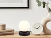 A modern desk setup with a lamp, clock, and books. Produktbild-Vorschau