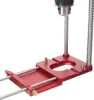 A close-up view of a red aluminum alloy drill locator for woodworking, with a drill chuck attached. Náhled obrázku produktu