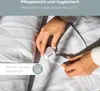 Hands connecting a detachable control unit to a white heated blanket. Produktbild-Vorschau