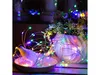 A string of colorful LED lights is wrapped around a small white bird figurine and a white vase with flowers. Podgląd zdjęcia produktu