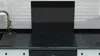 A black glass stove top cover is shown in a kitchen setting. Podgląd zdjęcia produktu