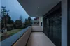 A modern balcony with a view of a garden and trees at dusk. Anteprima dell’immagine prodotto
