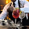 A bartender is preparing cocktails behind a bar, with three glasses of drinks in the foreground. Produktbild-Vorschau