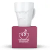A white mug with a grumpy face design sits on top of a pink box with the brand logo. Náhľad obrázku produktu