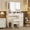 A white vanity table with a lighted mirror and a stool, set up in a room with decorative elements. Produktbild-Vorschau