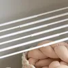 A close-up view of a white telescopic clothes rack with several horizontal bars, and a braided beige fabric item in a basket below. Produktbild-Vorschau