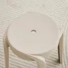 A close-up view of a beige stool on a textured rug. Voir les images du produit