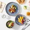 A top-down view of a table setting with plates of food, a salad bowl, and a glass of water. Náhled obrázku produktu