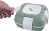 A hand is holding the handle of a green and white lunch thermos. Náhľad obrázku produktu