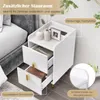 A white nightstand with two drawers is placed next to a bed. The top surface of the nightstand displays decorative items and a framed picture. Text overlays highlight product features. Produktbild-Vorschau