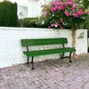 A green wooden garden bench sits in front of a white brick wall, with a flowering tree to the right and a manicured hedge to the left. Anteprima dell’immagine prodotto