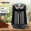 A black coffee pot with gold accents is shown on a wooden table, with a pile of coffee grounds in the foreground and a blurred garden scene in the background. Podgląd zdjęcia produktu