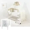 A white crib with bedding and a canopy, decorated with teddy bear and heart motifs. A teddy bear toy sits on a rug next to the crib. Produktbild-Vorschau