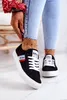A person wearing black Lee Cooper sneakers and blue jeans. Náhľad obrázku produktu