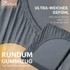 A close-up of a grey fitted sheet with text overlays highlighting its features. Produktbild-Vorschau
