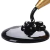 Black liquid being dispensed from a golden nozzle onto a white surface. Voir les images du produit