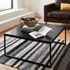 A living room scene with a coffee table, rug, and armchair. Produktbild-Vorschau