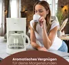 A woman is enjoying a cup of coffee next to a coffee maker. Anteprima dell’immagine prodotto