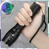 A hand holding a black flashlight with a wrist strap. Produktbild-Vorschau