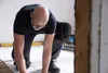 A man is kneeling on the floor, working on a tiling project. He is wearing knee pads. Anteprima dell’immagine prodotto