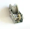 A close-up studio shot of a metal winch with a steel cable wound around it, set against a plain white background. Produktbild-Vorschau