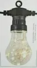 A close-up of a single LED light bulb string light with a clear glass bulb containing warm white wire lights. Produktbild-Vorschau