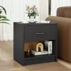 A dark gray nightstand with a drawer and an open shelf is placed next to a brown sofa, with a bouquet of pink flowers and a cup of coffee on top. The shelf contains books and decorative items. Podgląd zdjęcia produktu