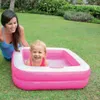 A woman is watching a young girl play in a pink inflatable pool on a grassy lawn. Produktbild-Vorschau