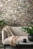 A living room scene with a sofa, throw blanket, and plants, featuring a stone-patterned wallpaper. Produktbild-Vorschau