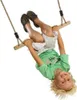 A young boy is upside down on a wooden trapeze swing. Anteprima dell’immagine prodotto