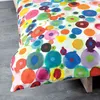 A close-up view of a duvet cover with a colorful, abstract polka dot and circle pattern. Produktbild-Vorschau