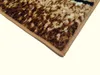 A close-up view of the corner of a rug with a brown and beige pattern. Náhled obrázku produktu