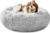 A small dog is lying on a fluffy gray dog bed. Produktbild-Vorschau