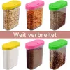 A collage of six clear plastic storage containers with colored lids, each filled with different food items or spices. Produktbild-Vorschau