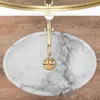 A close-up overhead view of a marble sink with a gold faucet. Produktbild-Vorschau