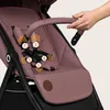 A hand is shown adjusting the harness of a pink stroller. Produktbild-Vorschau