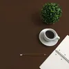 A flat lay of a desk with a cup of coffee, a plant, a notebook with a graph, and a pencil. Produktbild-Vorschau