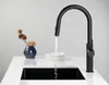 A black kitchen faucet with water running into a black sink. Náhľad obrázku produktu