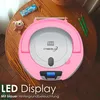 A pink CD player with a digital display sits on a wooden table, next to a small teddy bear and some candies. Two green pencils are also visible on the table. Voir les images du produit