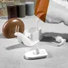 A white snail-shaped soap dispenser is being filled with white liquid from a pouch, next to a brown snail shell and some candles. Voir les images du produit