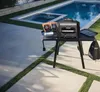 An electric grill is set up on a table next to a swimming pool. Voir les images du produit