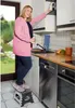 A woman is standing on a stool in a kitchen, reaching for a cabinet. Podgląd zdjęcia produktu