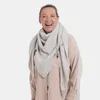 A woman wearing a beige scarf. Produktbild-Vorschau