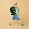 A young boy wearing a backpack and a cap, posing against a plain background. Produktbild-Vorschau