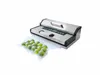A vacuum sealer machine with a bag of green items, possibly fruits or vegetables, next to it. Podgląd zdjęcia produktu